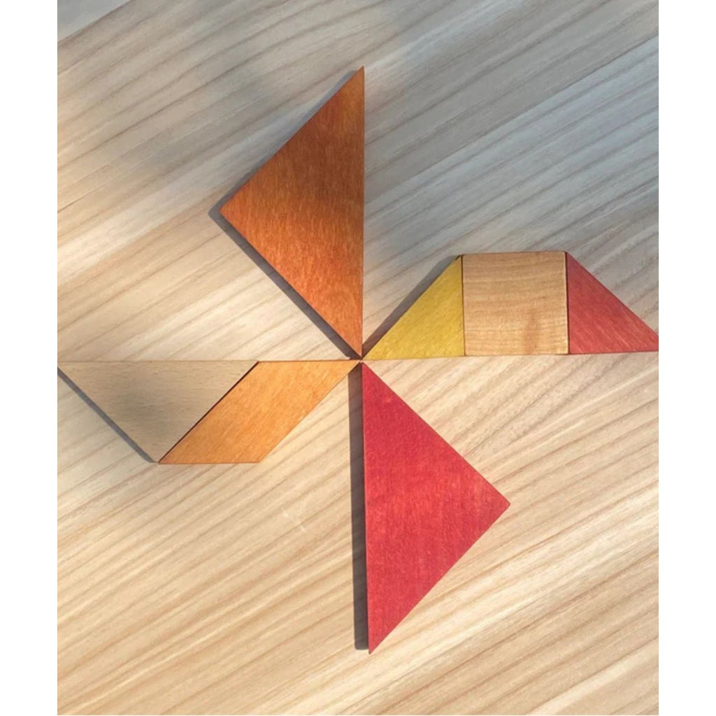wooden tangram puzzle pieces neatly arranged on a table beside its practical travel bag