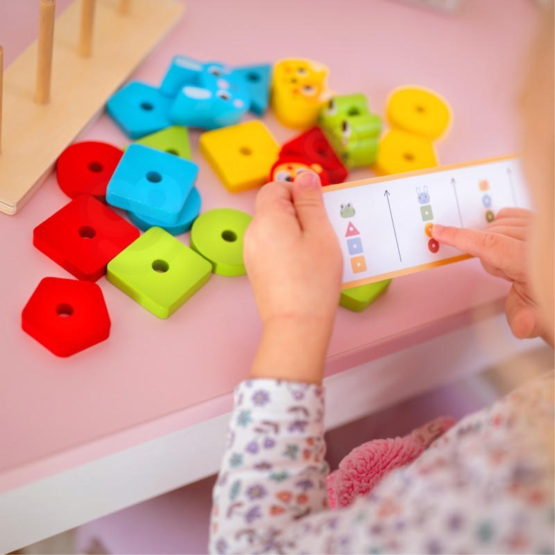 close-up of a child's hands stacking the durable wood animal puzzle pyramid blocks on the base