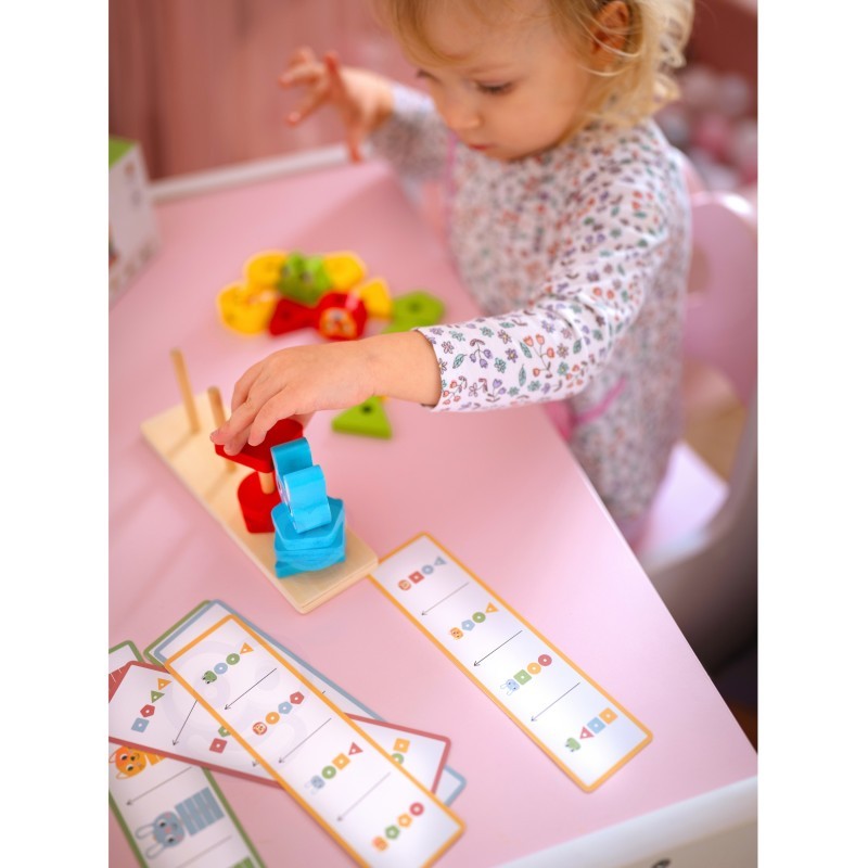 a child's hand placing a wooden giraffe block onto the montessori puzzle pyramid