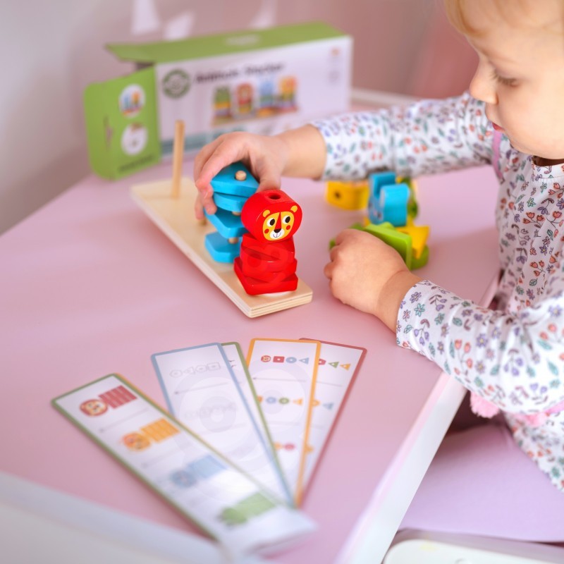 a child's hand placing a wooden giraffe block onto the colorful montessori puzzle pyramid