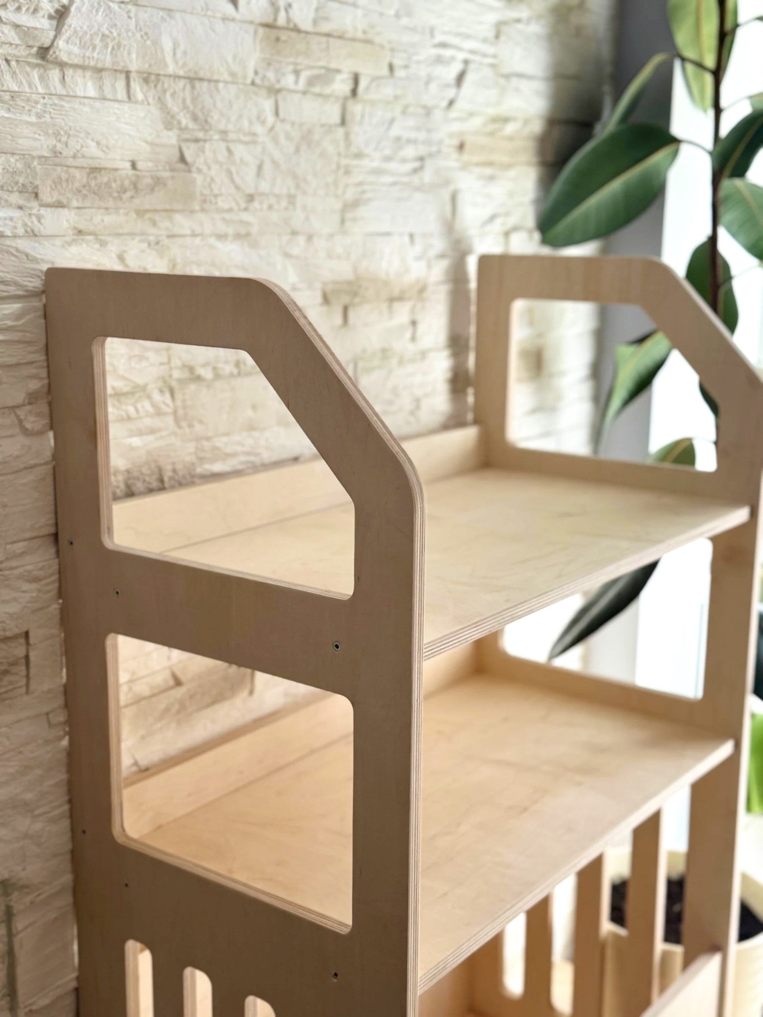 a playful toddler reaching for a book on the bottom shelf of their wooden montessori storage