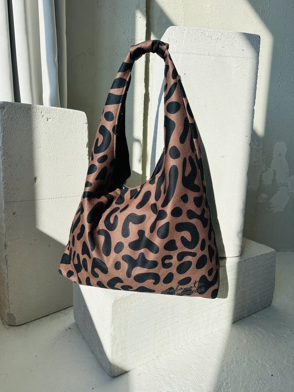 functional leopard print moon bag open to show its spacious interior and garbonata-lined zippered pocket