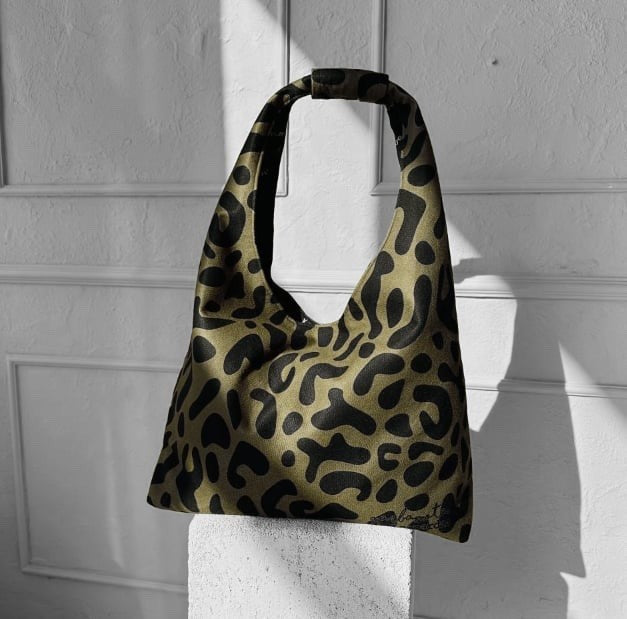 bold khaki leopard moon bag heart in a dramatic front-angle shot showcasing its wild pattern