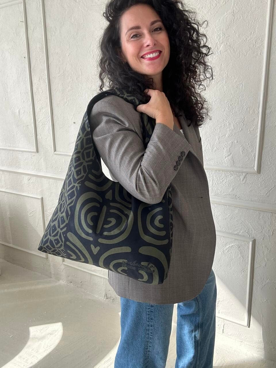 confident woman modeling the bold khaki pattern moon bag against an urban backdrop