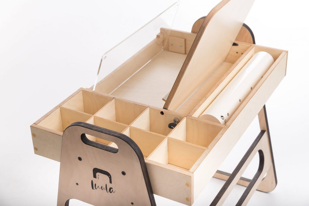 a child's functional julle art table with open storage boxes and a paper roll ready for creative projects