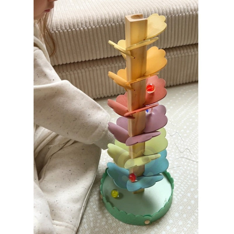 elegant close-up of a wooden rainbow ball track with pastel balls on a soft-focus natural background
