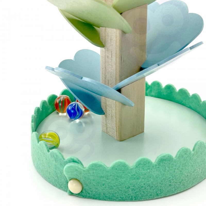 a child's hand guiding a colorful ball down the rainbow track in soft morning light