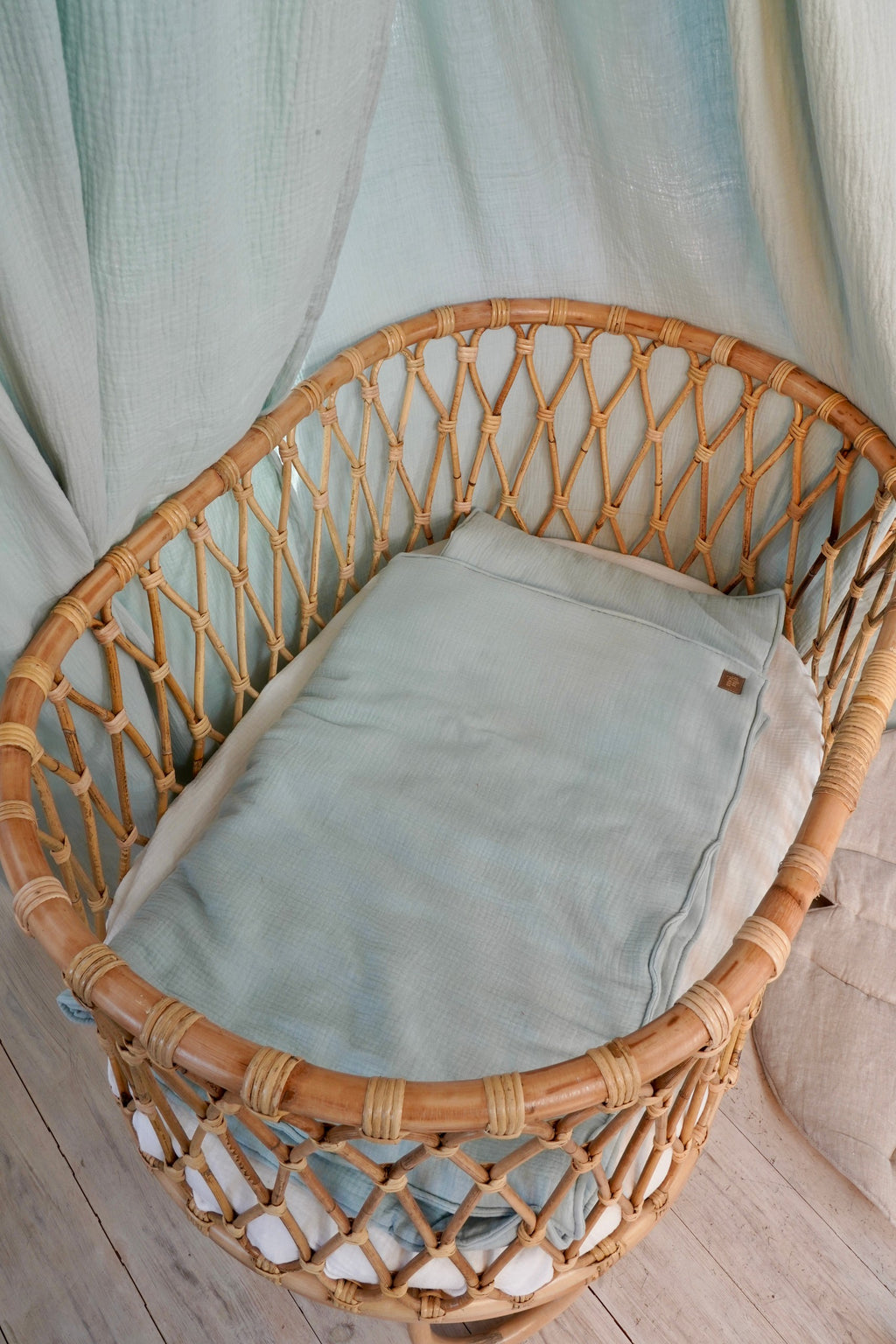 bold mint muslin baby blanket and pillow set laid flat on a rustic wooden surface, showcasing its generous size and handmade craftsmanship