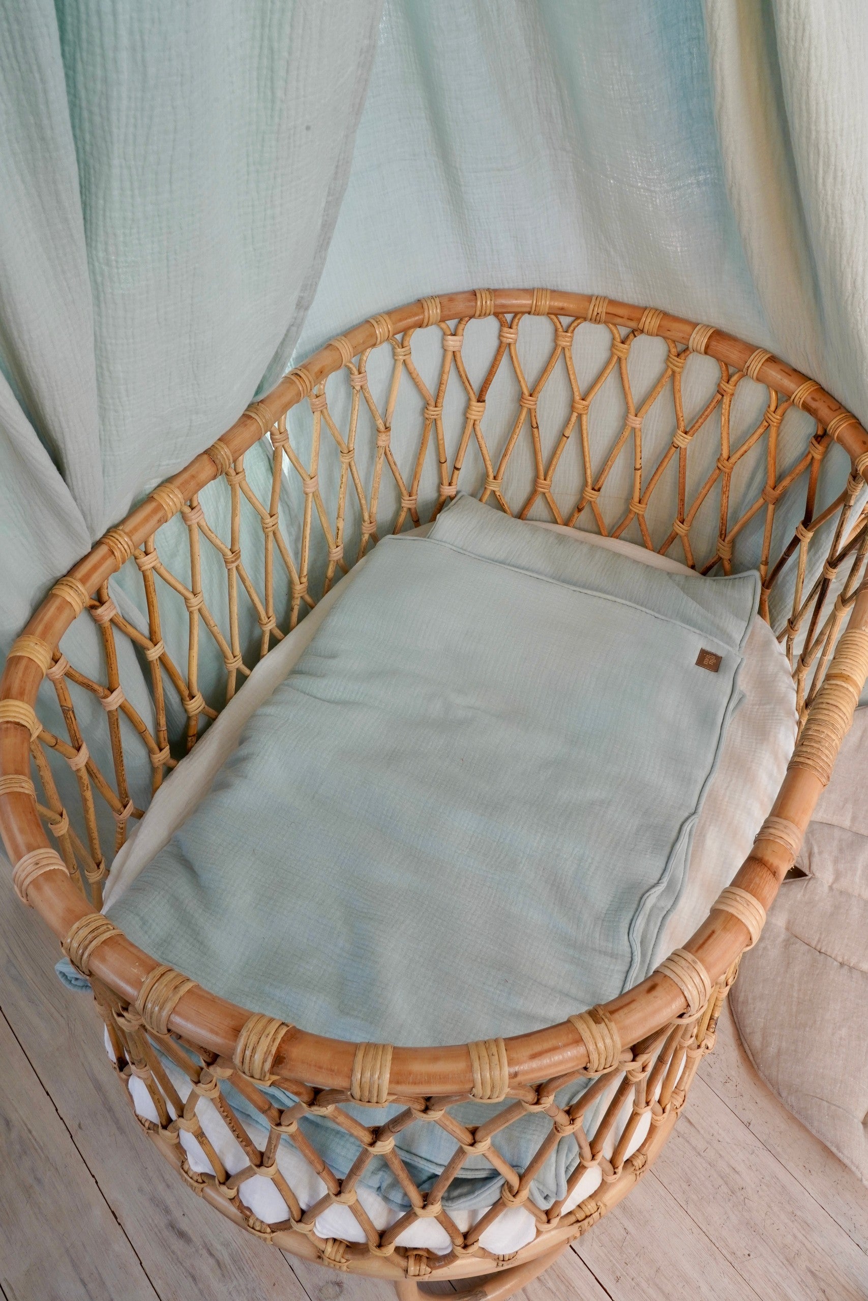 bold mint muslin baby blanket and pillow set laid flat on a rustic wooden surface, showcasing its generous size and handmade craftsmanship