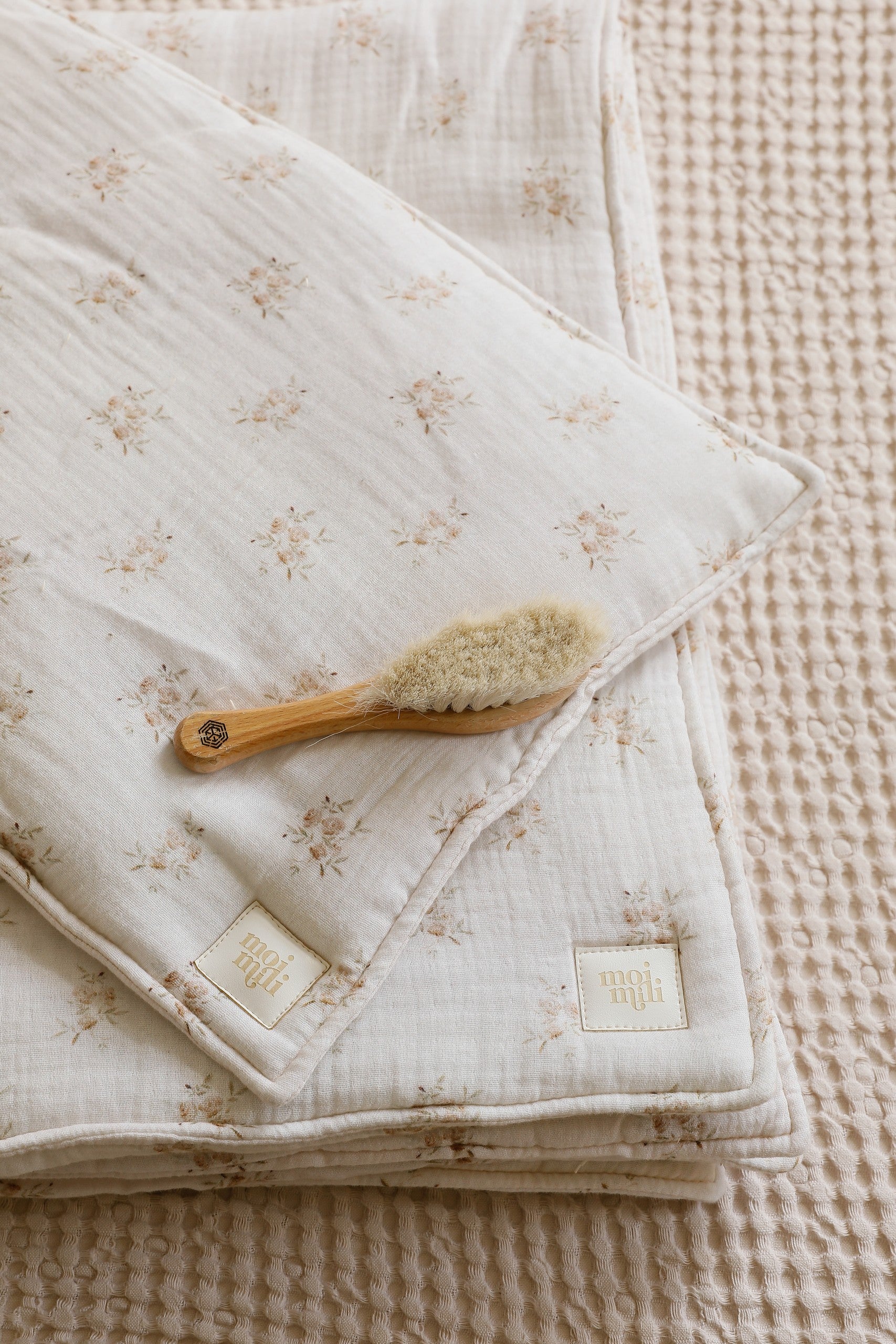 elegant boho flower muslin baby blanket and pillow set on a neutral linen backdrop, soft and refined