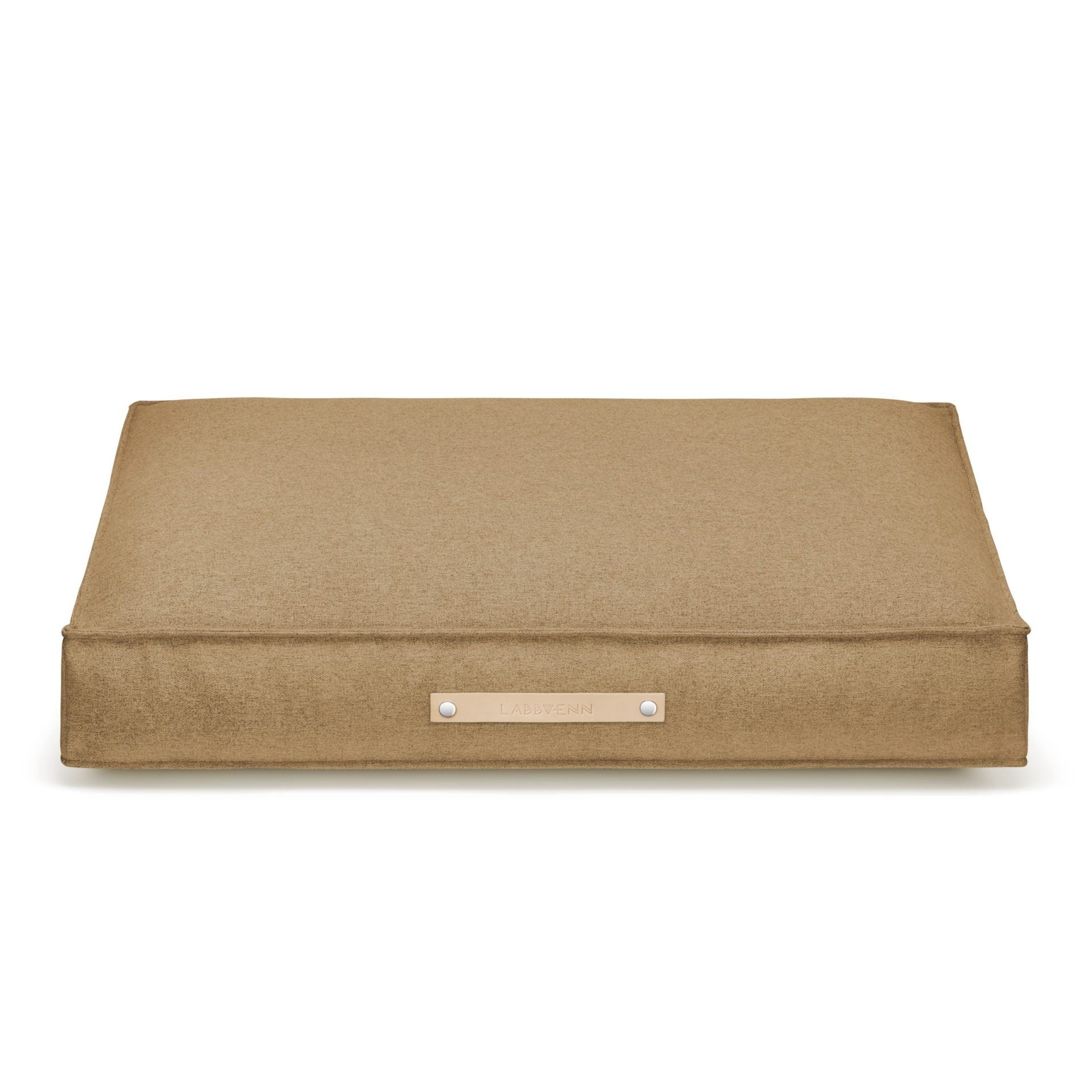 bold møvik dog cushion in biscuit on a dark slate floor, showcasing its modern design