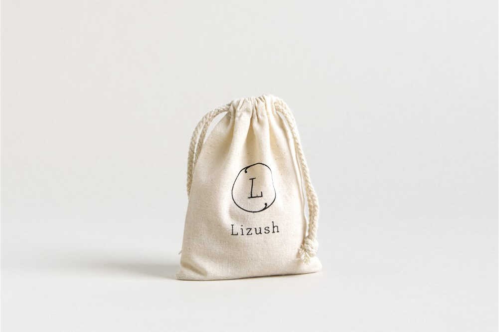 elegant glass jar of organic nipple balm nestled in a soft cotton pouch