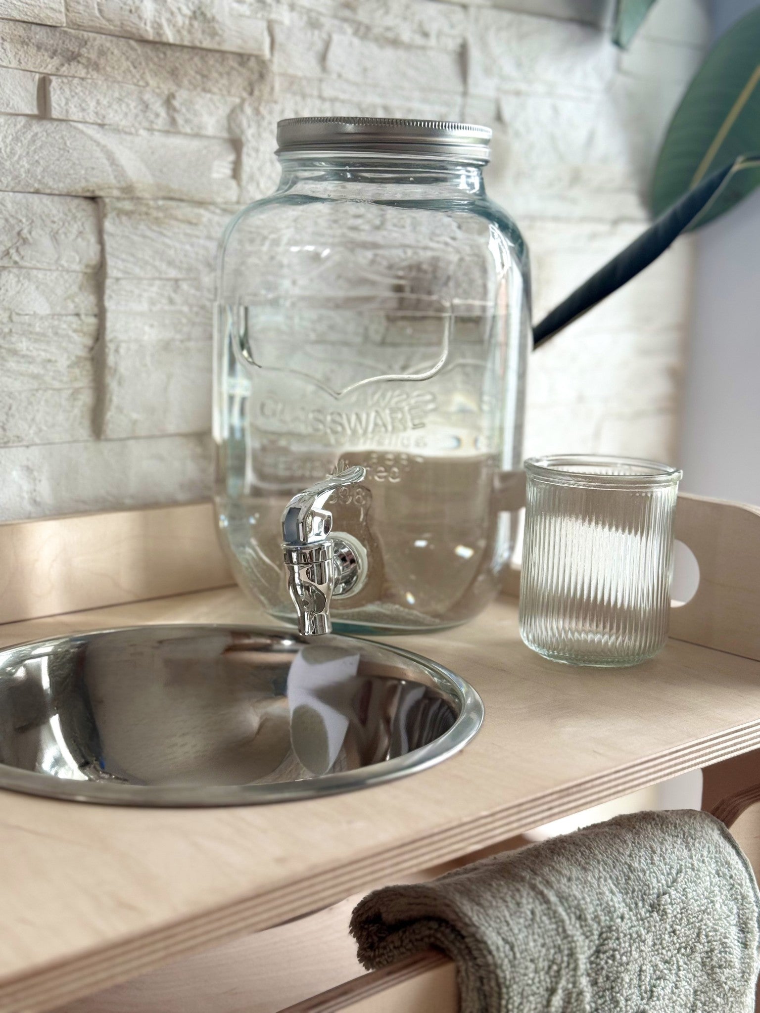 a child's hand splashing water in the enamel bowl of a playful wooden washbasin