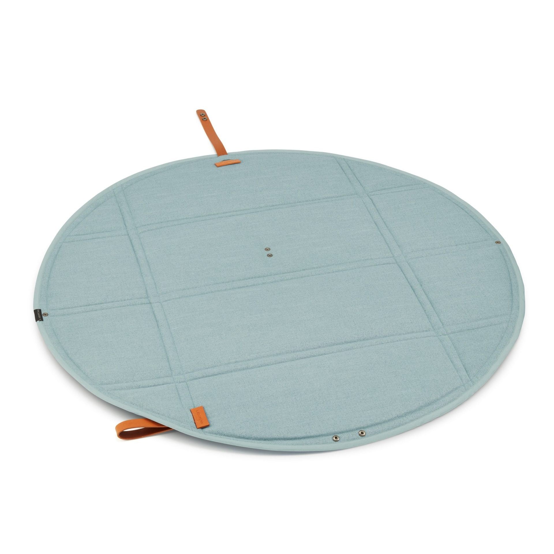 a soft teal dog travel mat with elegant leather accents laid out on a peaceful grassy field