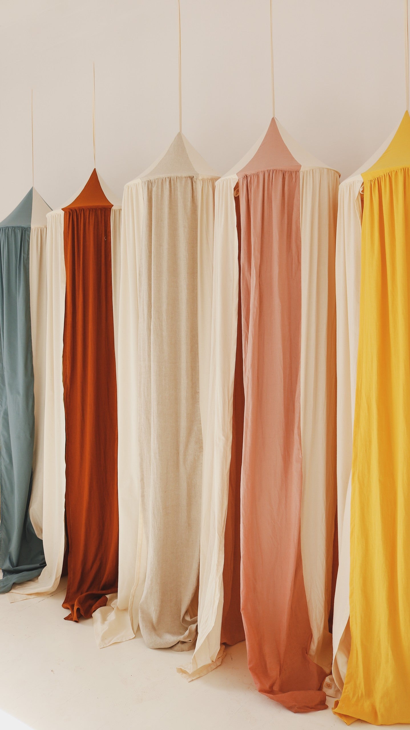 playful cream circus organic cotton and linen canopy hanging over a cozy reading nook with soft light filtering through