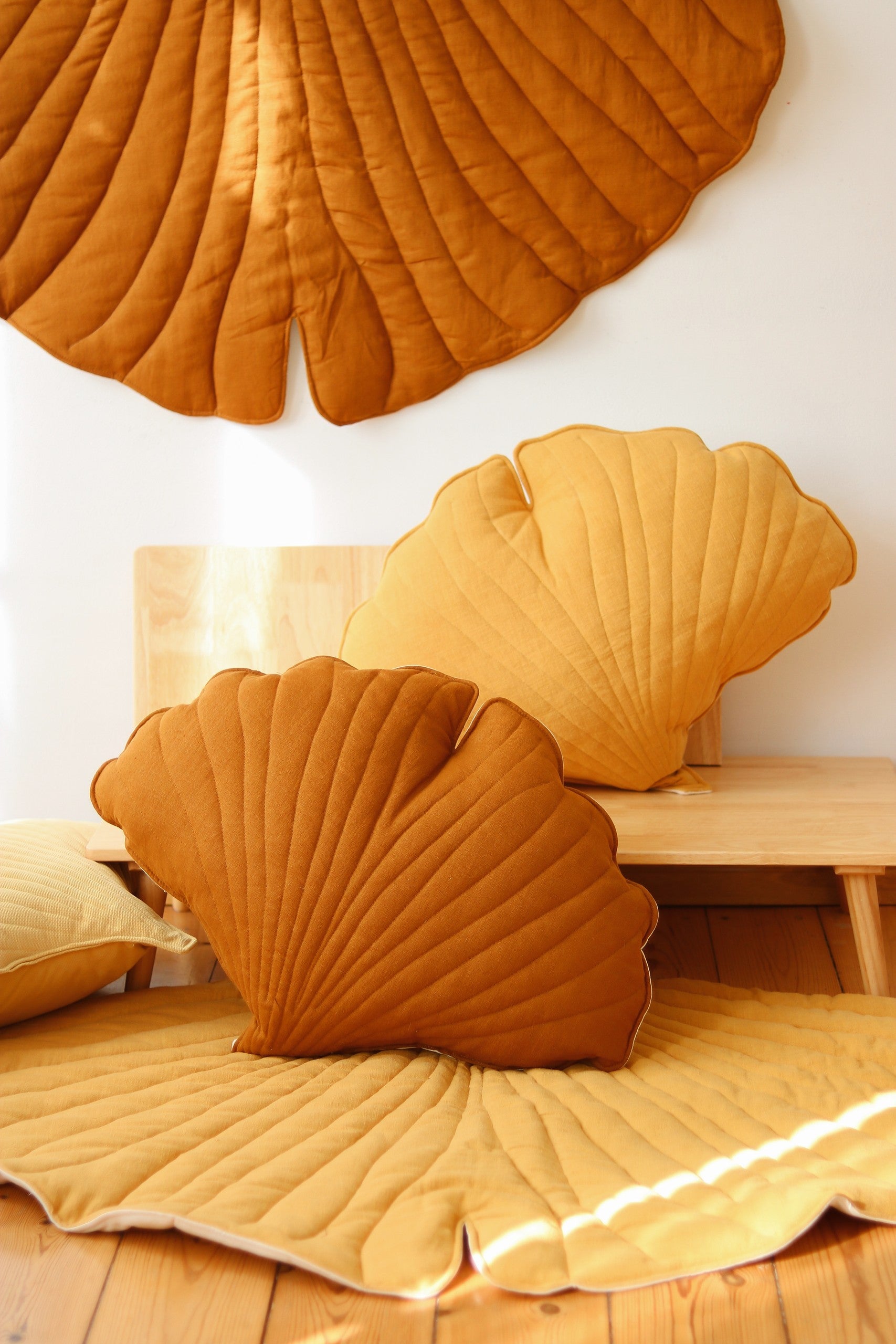 bold caramel ginkgo leaf playmat on a dark floor, showcasing its elegant handmade texture
