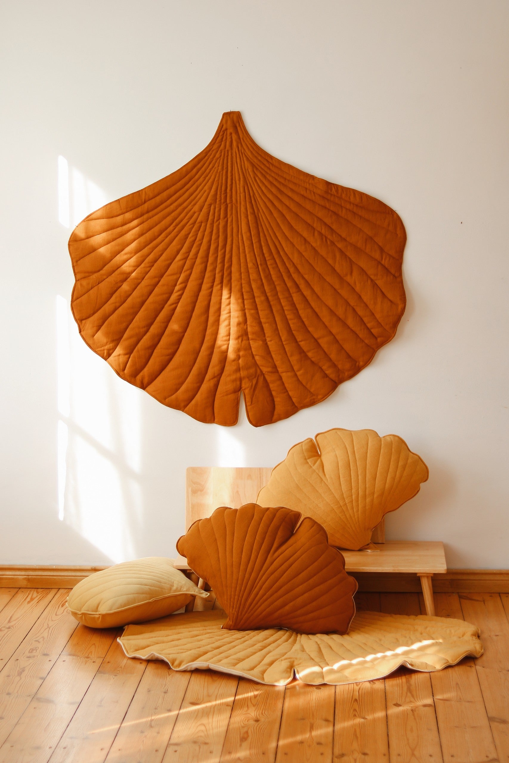 elegant caramel ginkgo leaf playmat on a hardwood floor, showcasing its refined handmade texture