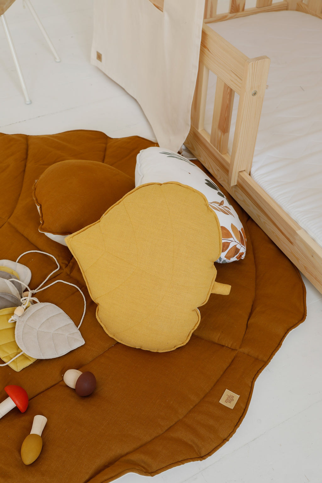a child's hand tracing the textured caramel ginkgo leaf playmat on a hardwood floor
