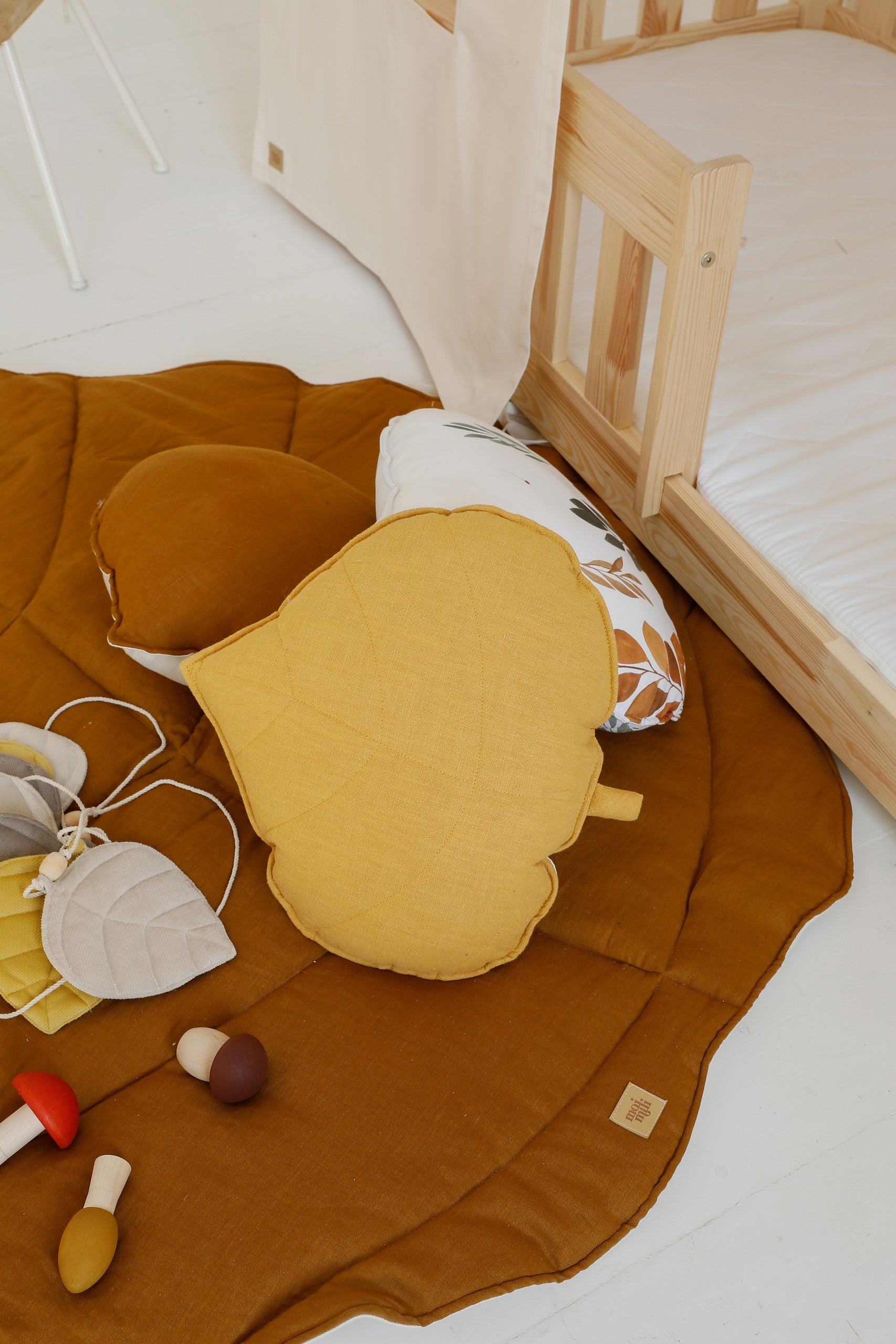 a child's hand tracing the textured caramel ginkgo leaf playmat on a hardwood floor