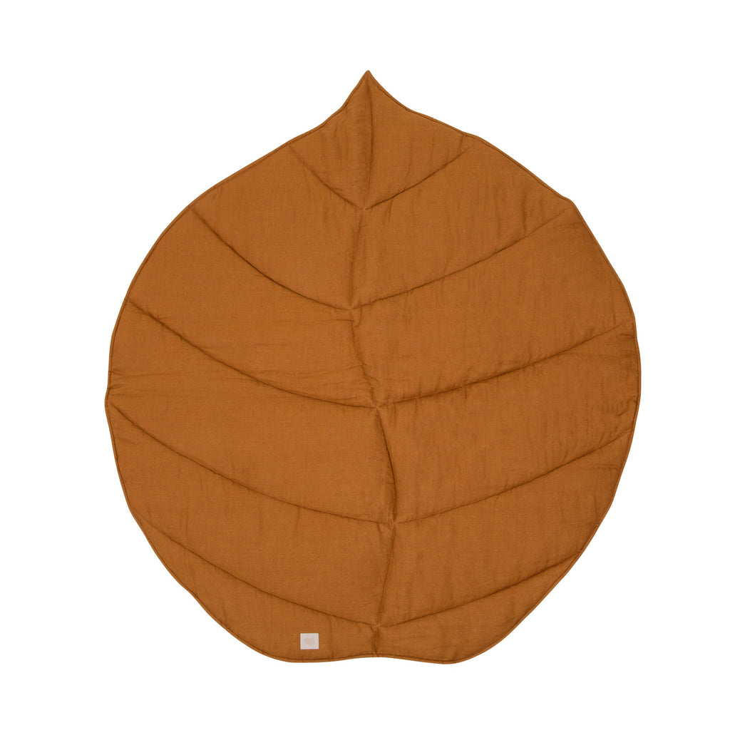 a child's hand tracing the textured caramel linen surface of a handmade ginkgo leaf playmat
