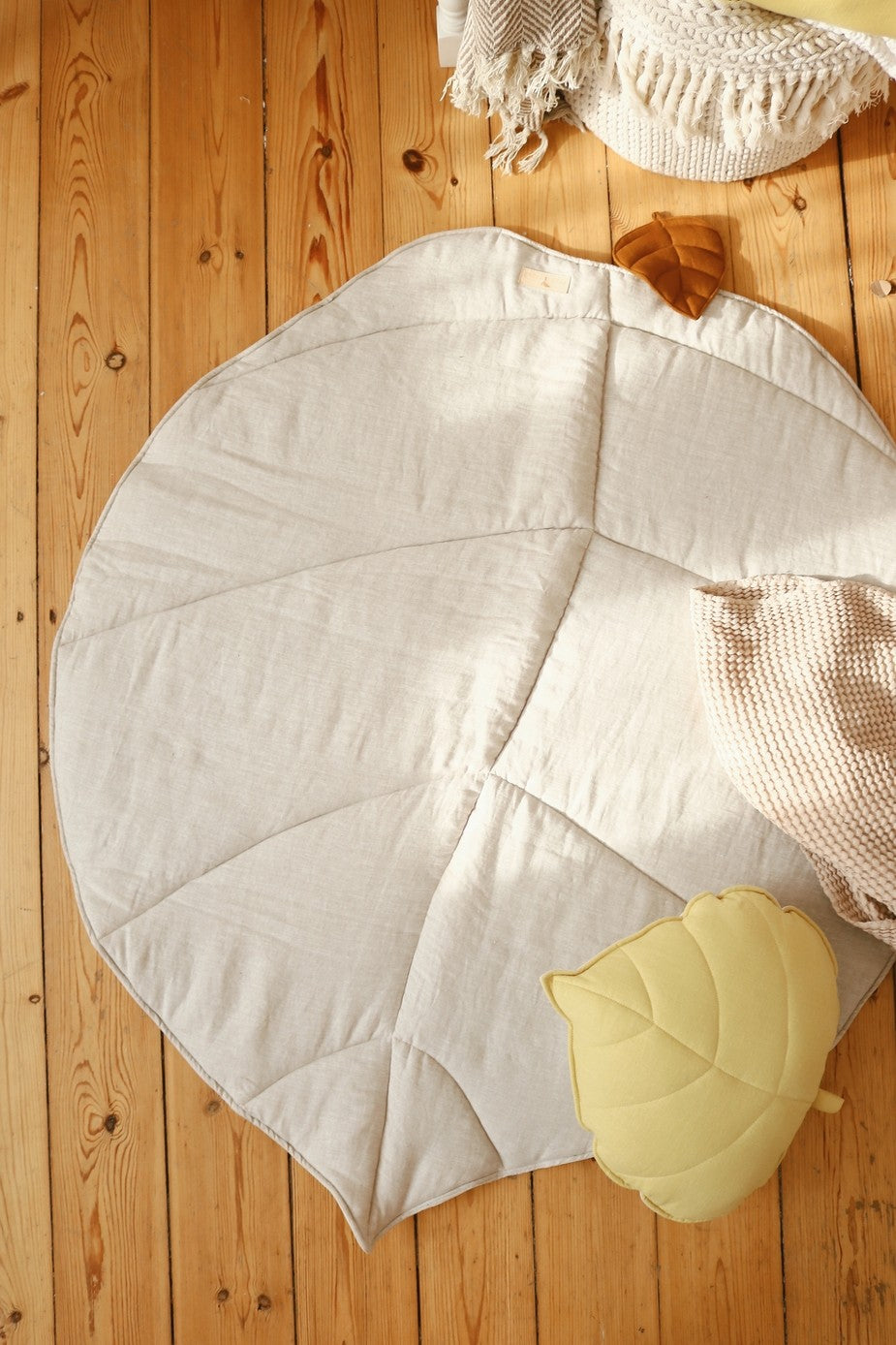 a close-up detail of the ginkgo leaf playmat's textured organic cotton and linen weave in a soft sand color