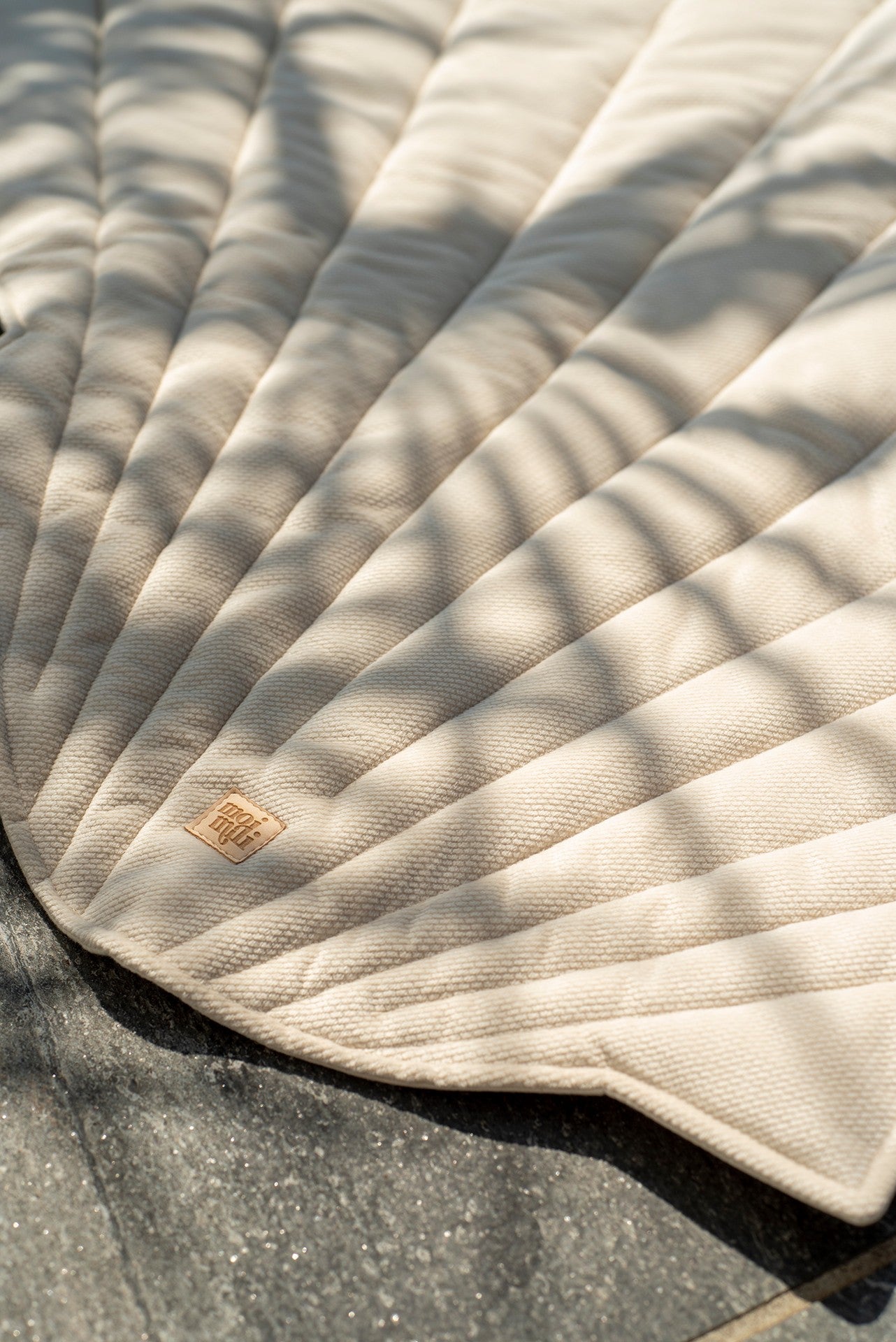 beige organic cotton and velvet ginkgo leaf playmat laid on grass under dappled sunlight