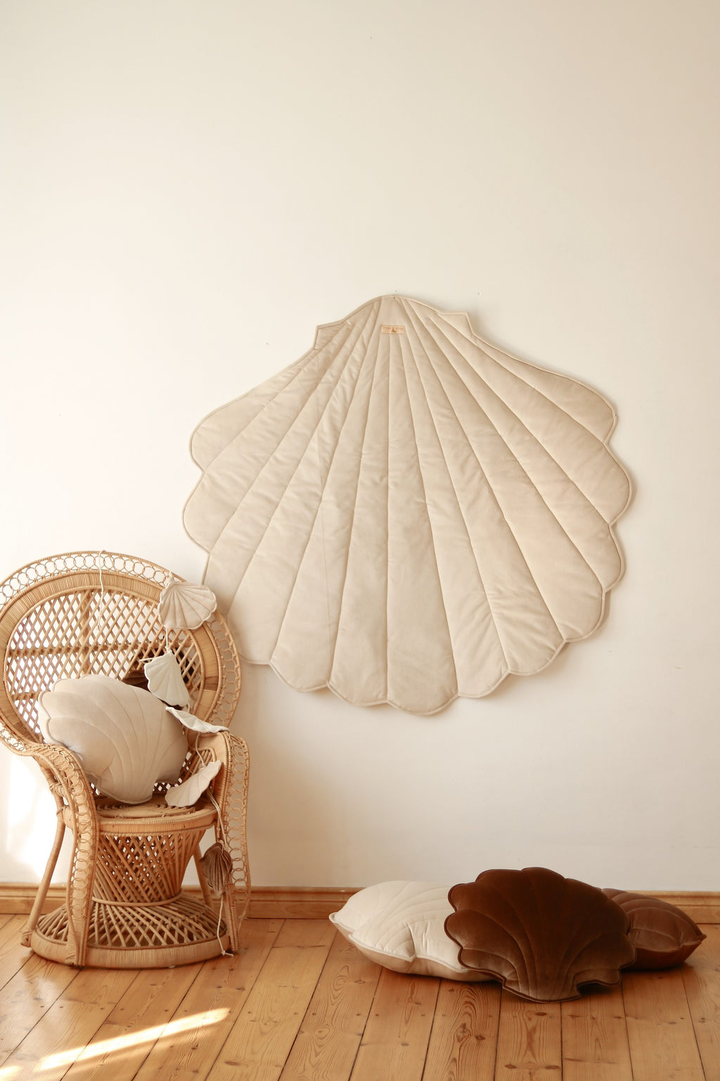 handmade beige ginkgo leaf playmat on a wooden floor, showcasing its plush texture and elegant shape