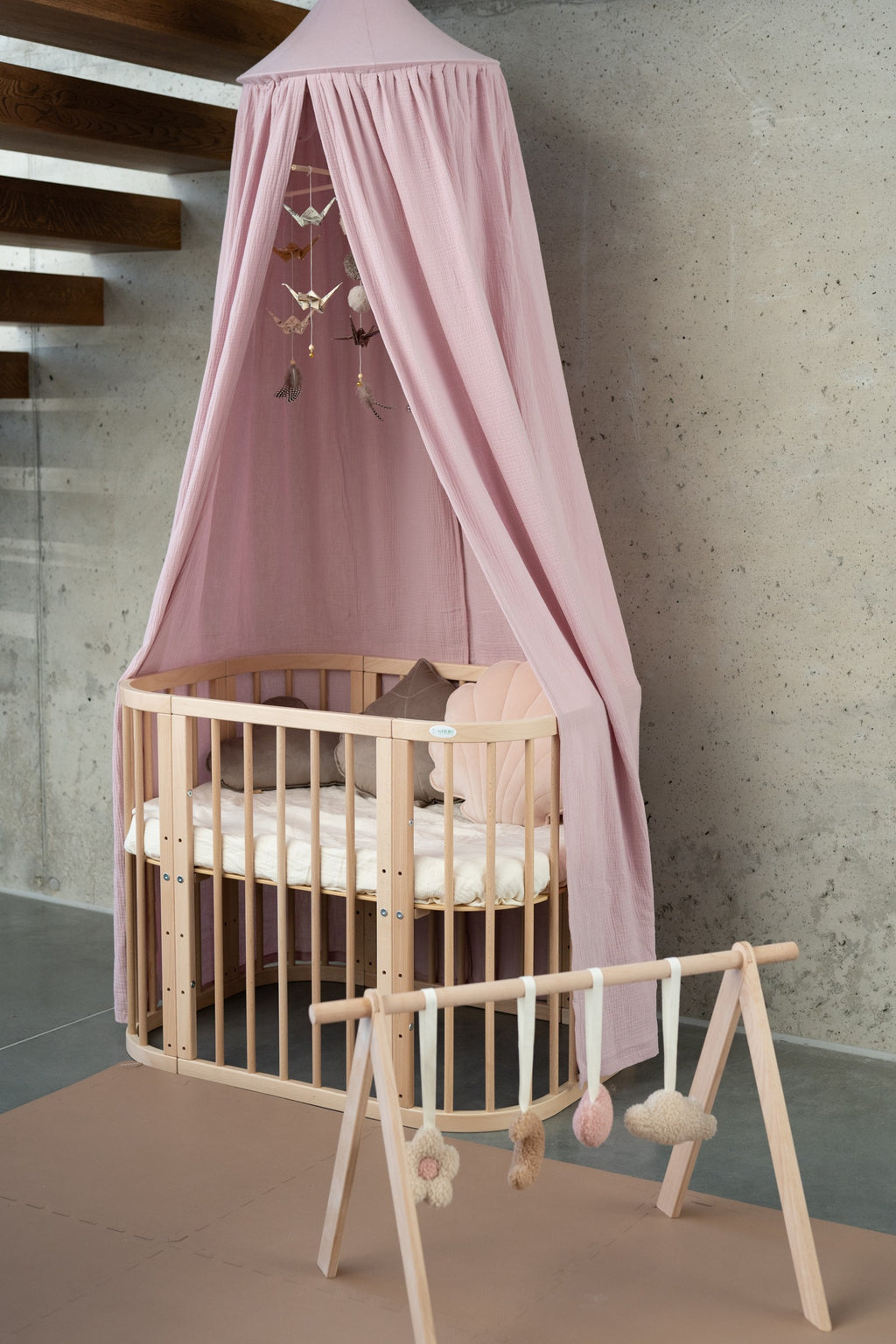 soft baby pink organic cotton canopy draped gently over a cozy reading nook, with natural light filtering through