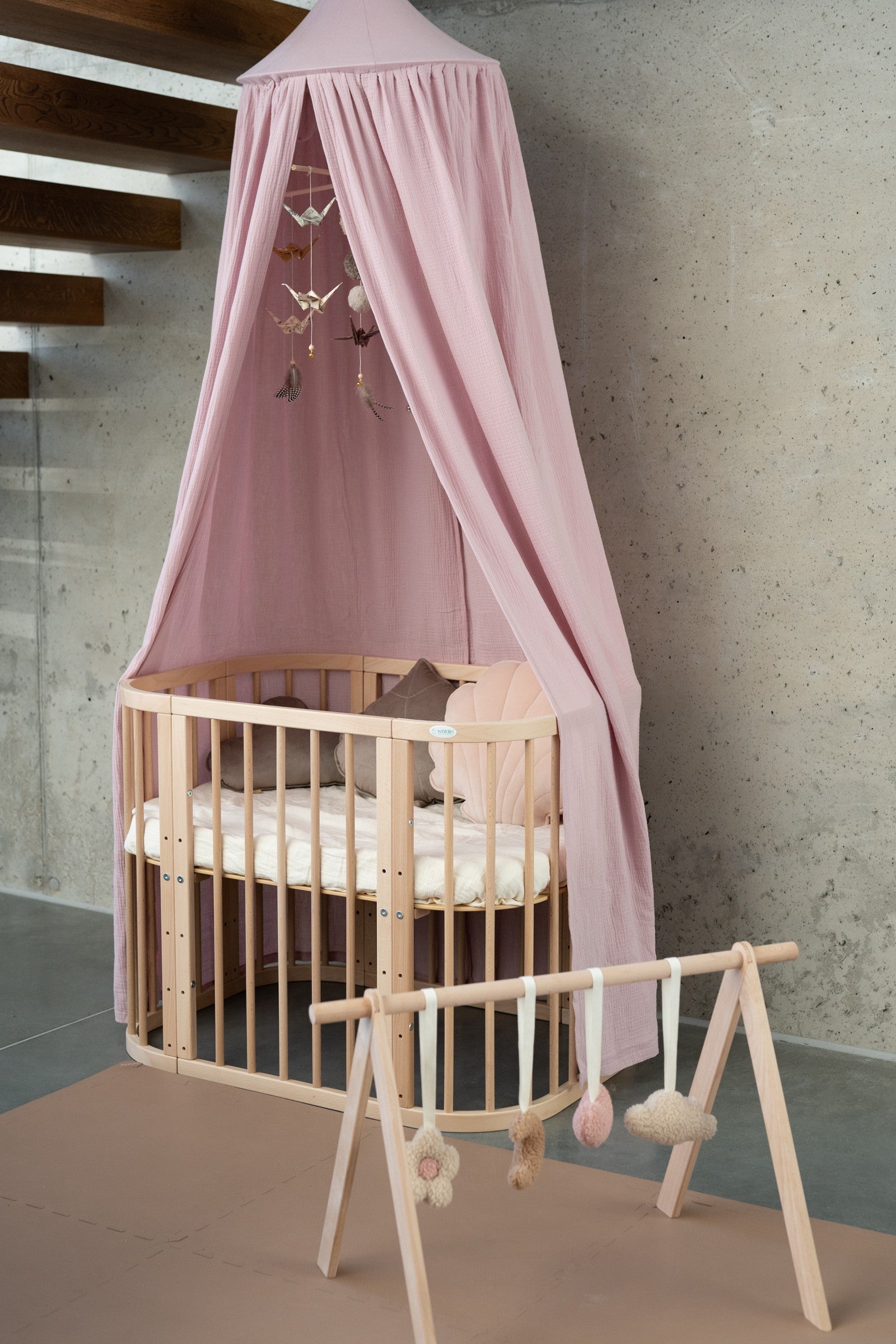 soft baby pink organic cotton canopy draped gently over a cozy reading nook, with natural light filtering through