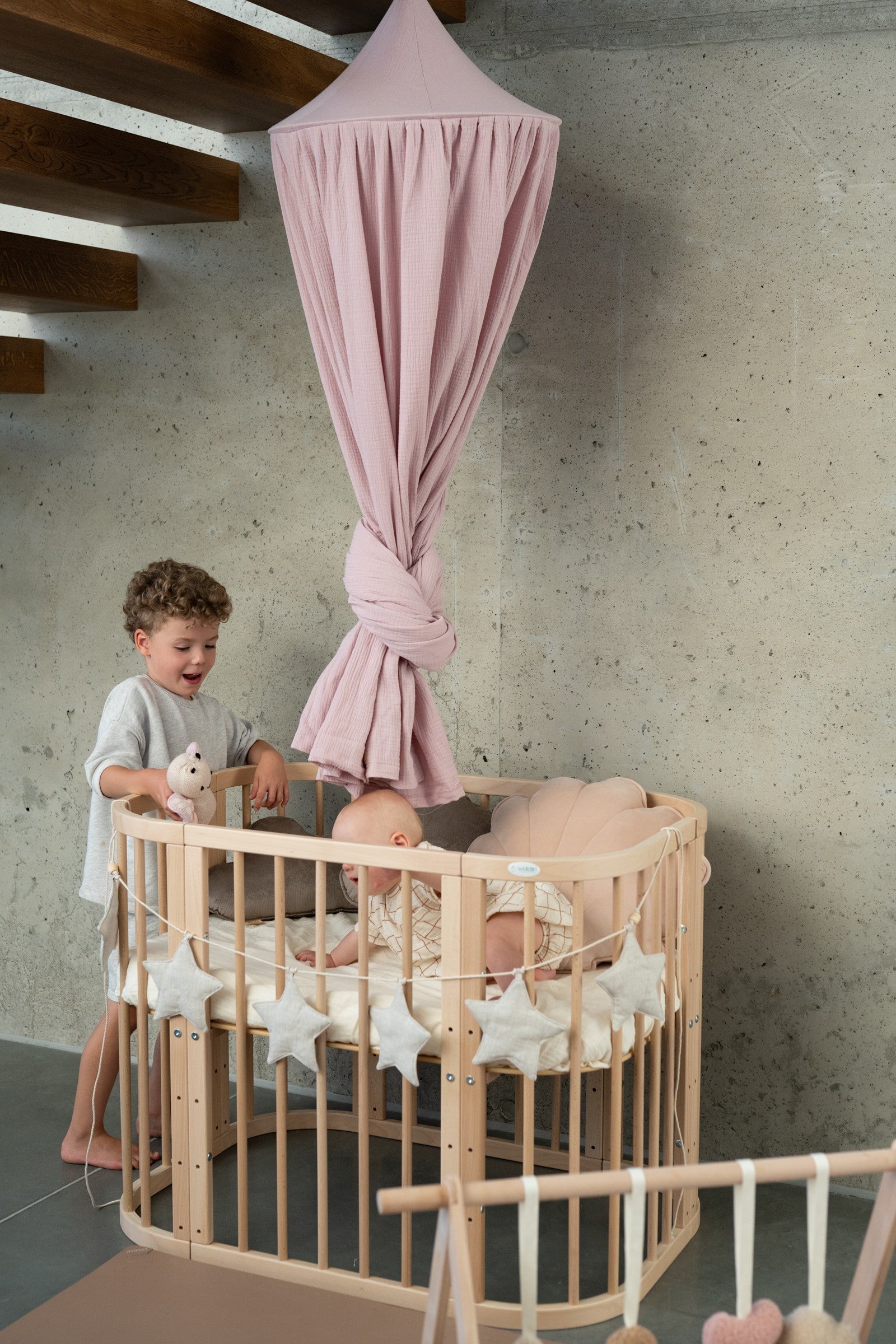 elegant baby pink organic cotton canopy hanging gracefully over a cozy reading nook with soft lighting