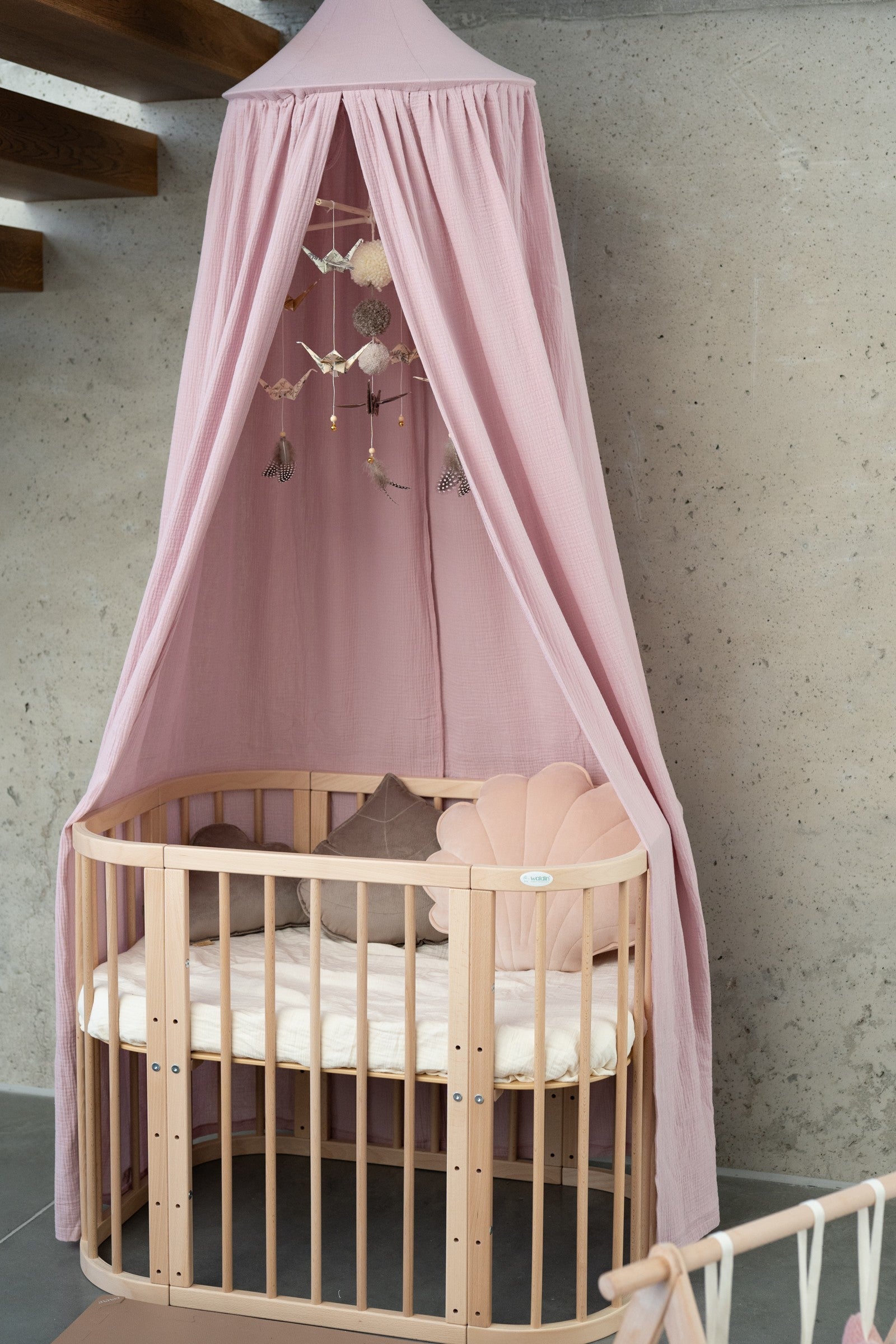 baby pink organic cotton canopy hanging over a bed with soft morning light