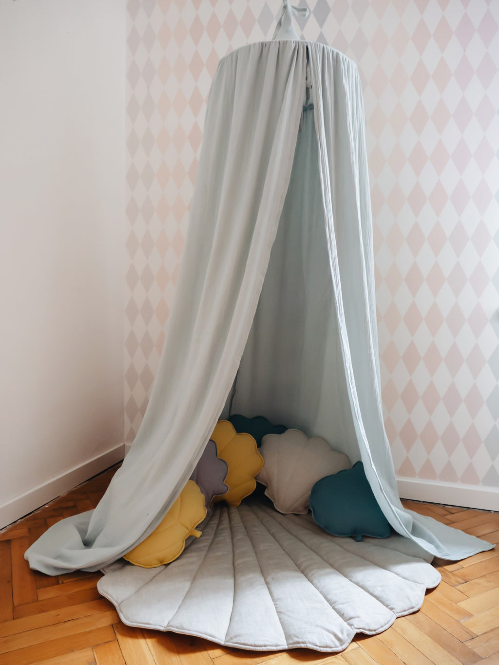 a playful mint green cotton canopy hung over a child's bed with soft toys peeking out from underneath