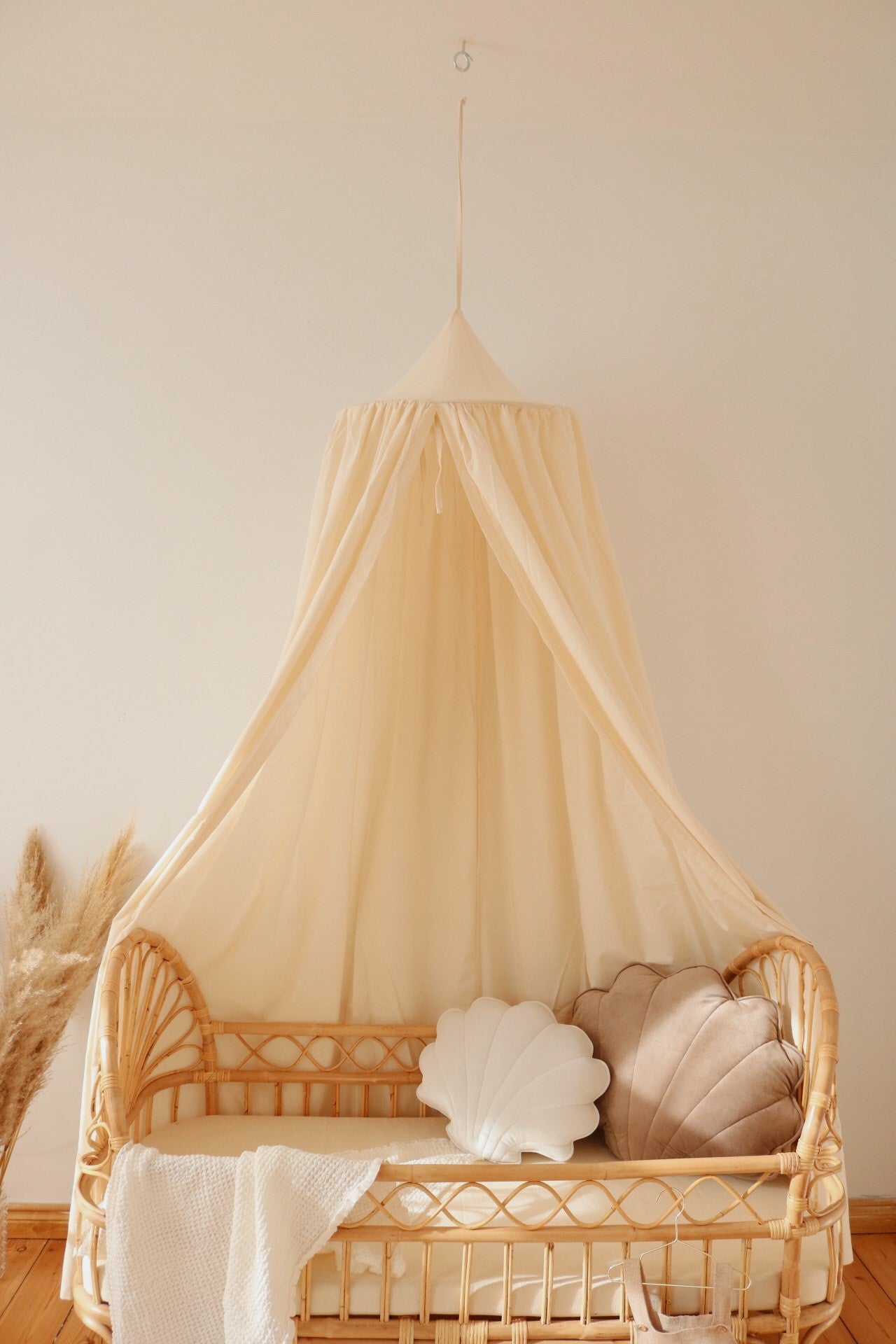soft organic cotton canopy hanging over a cozy reading nook with natural light filtering through