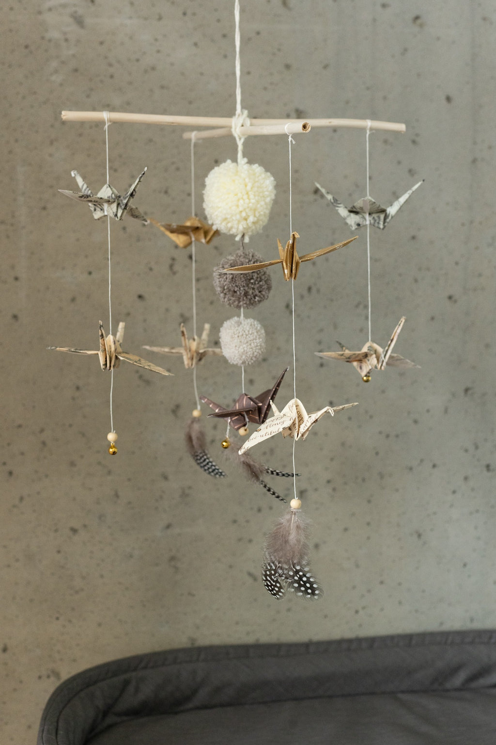 gold dust origami nursery mobile with delicate paper cranes and soft pompoms gently spinning in warm light