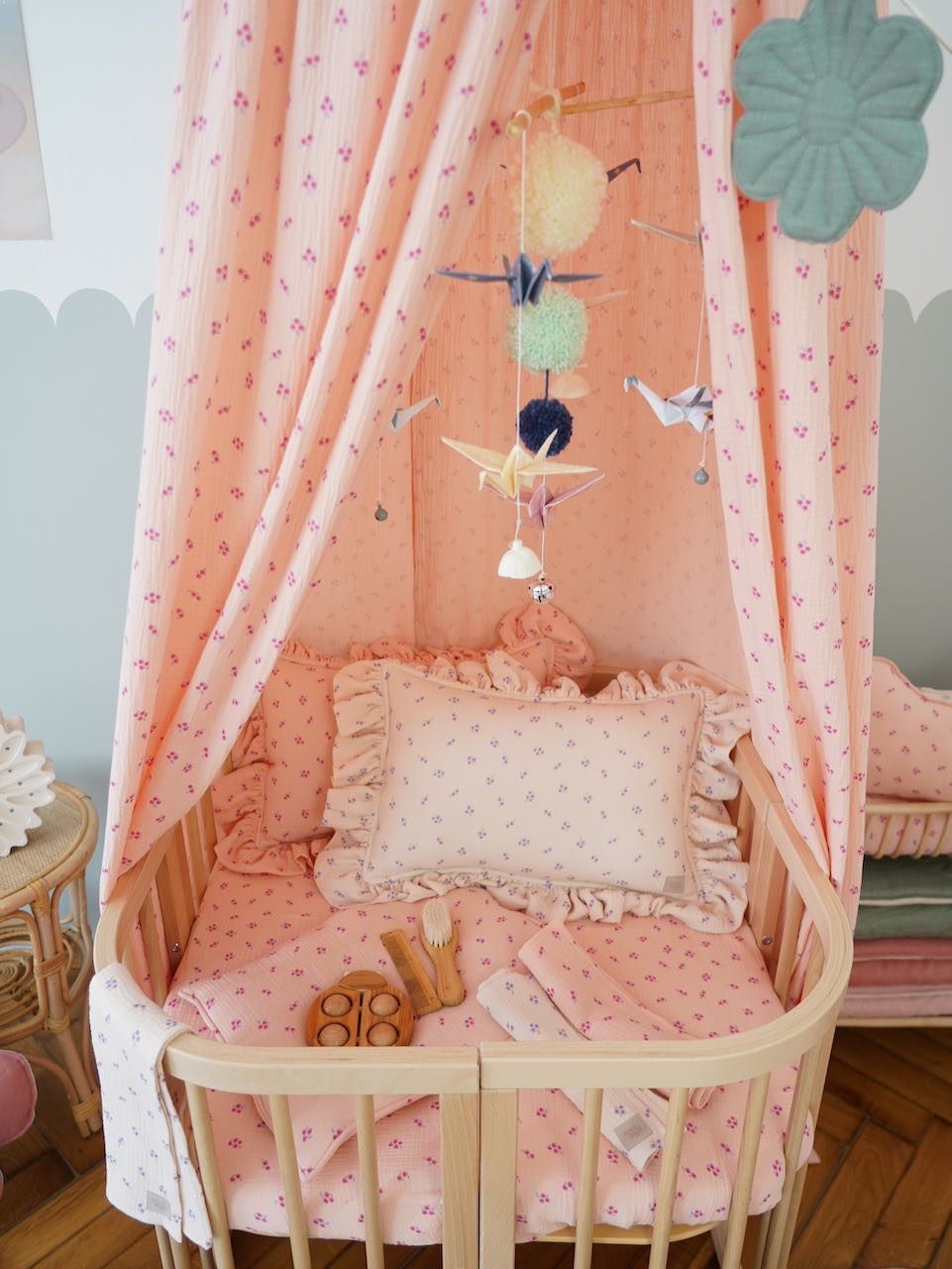 handmade pastel origami mobile with delicate cranes and pompoms swaying gently above a crib