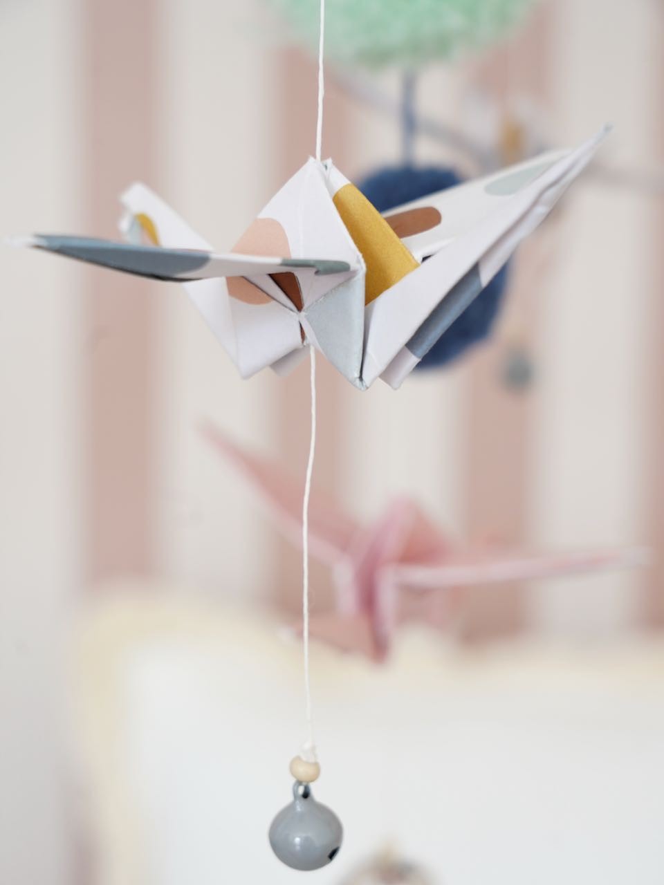 elegant handmade origami mobile with soft pastel paper cranes and yarn pompoms