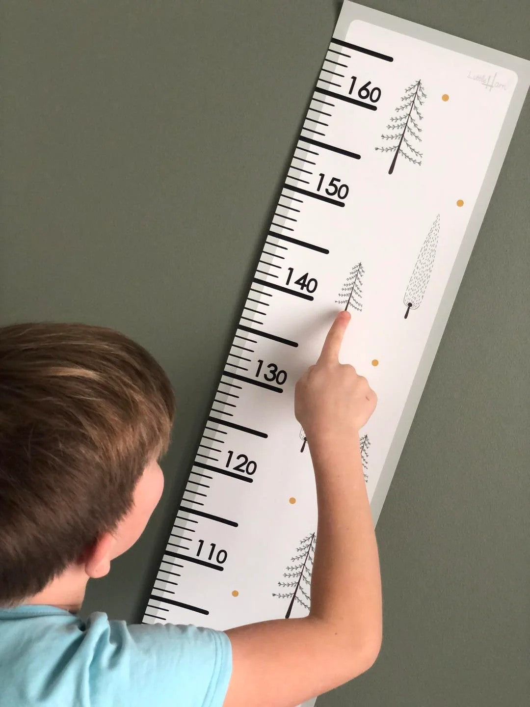 a bold minimalist fir trees growth chart for kids mounted on a clean white wall