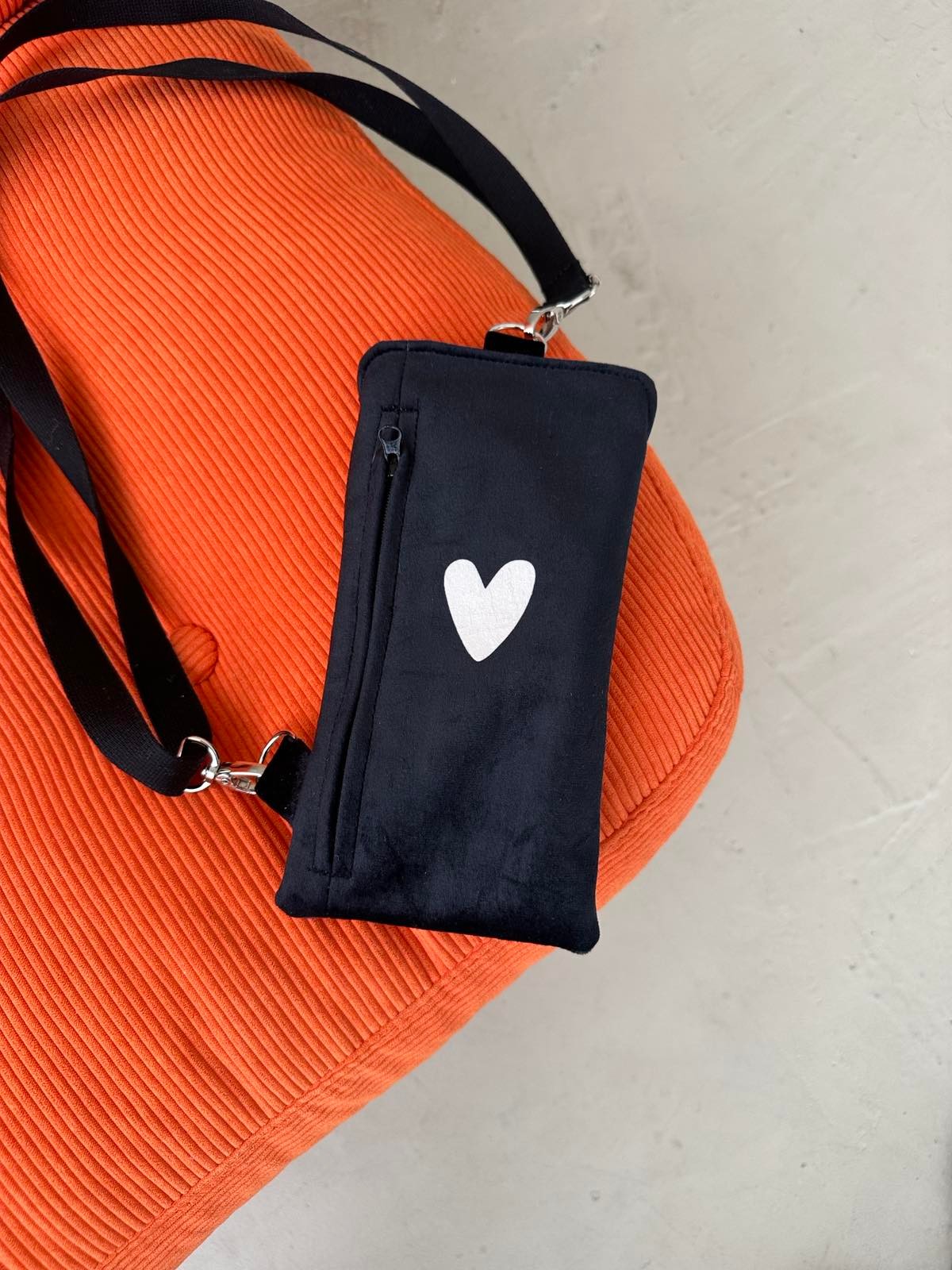 playful close-up of a chic black heart phone bag with a fun, textured velour finish
