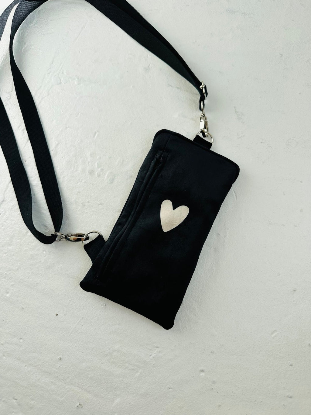 elegant black velour heart phone bag with a metal clasp, shown in soft, refined lighting