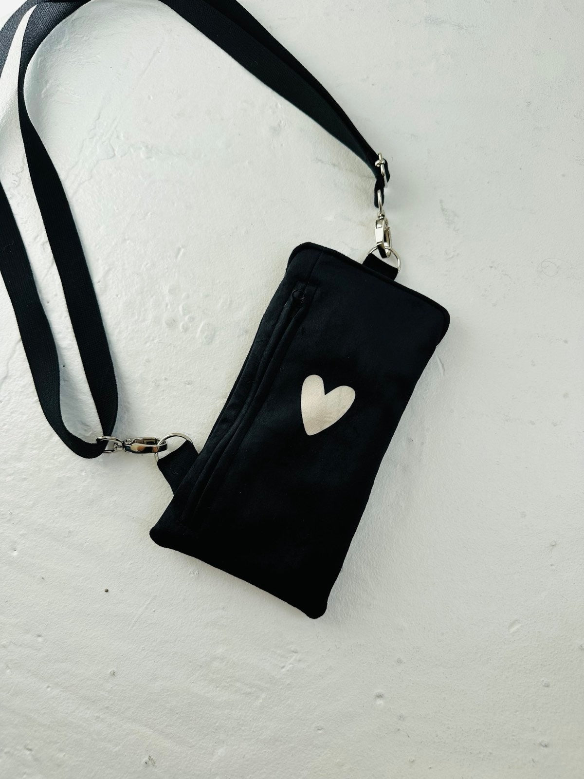 elegant black velour heart phone bag with a metal clasp, shown in soft, refined lighting