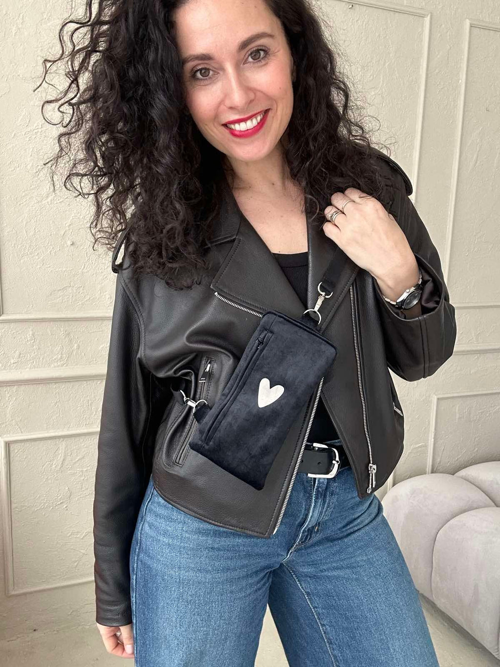 confident woman modeling a chic black heart phone bag with a bold velour texture