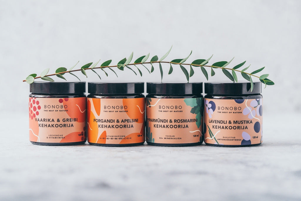 a contemporary leather gift box holding four velvety body scrubs in warm, inviting light