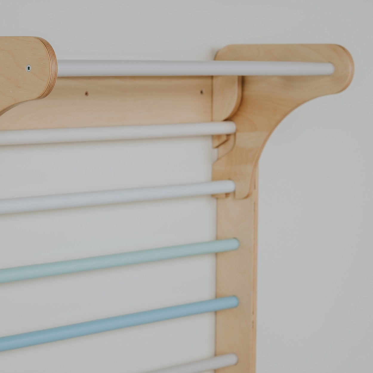 a child's hand reaching for the pastel climbing wall in soft morning light