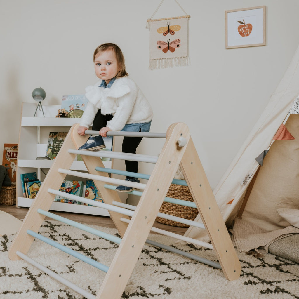 a bold, low-angle shot of a child conquering the pastel climbing triangle, showcasing strength and confidence