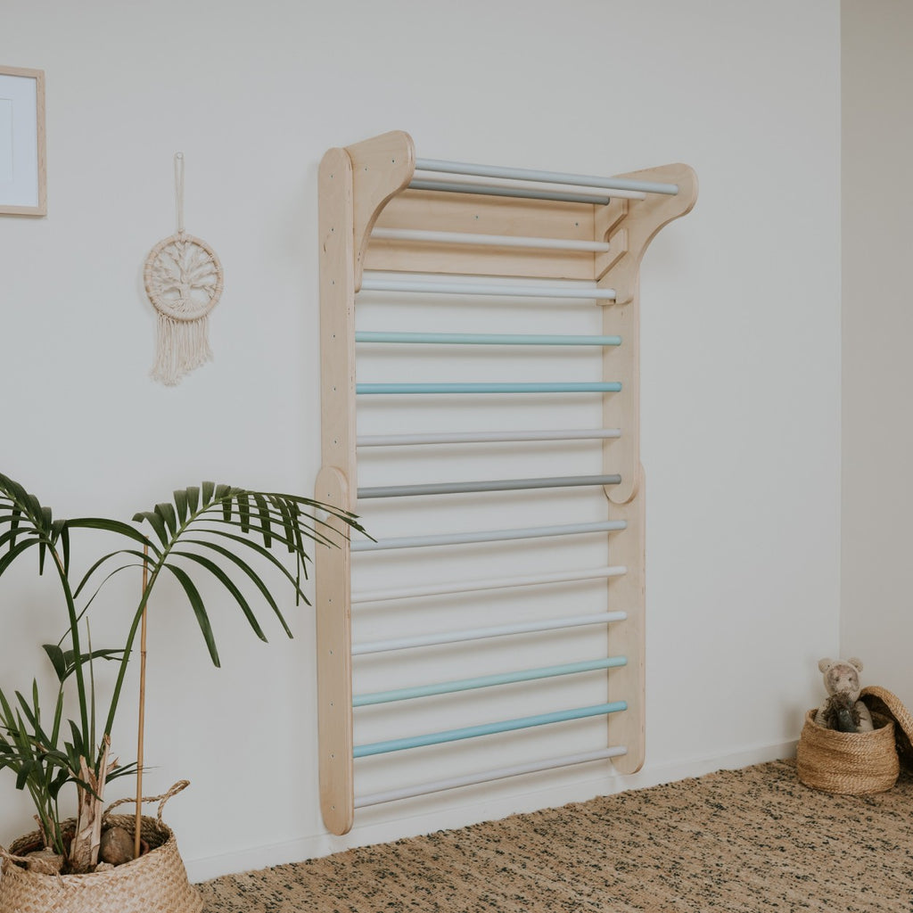 a child's hand reaching for the pastel climbing wall in soft morning light