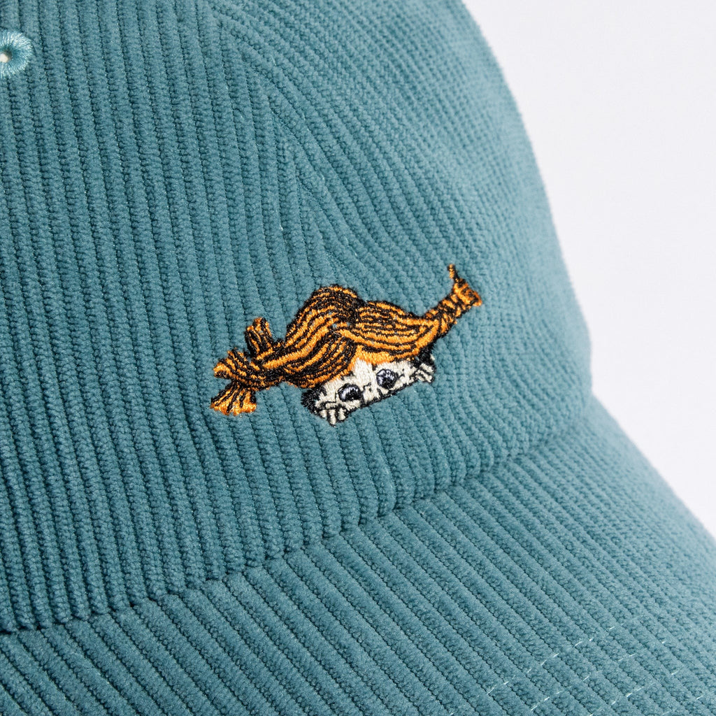 a playful petrol blue corduroy dad cap tilted on a sunny park bench