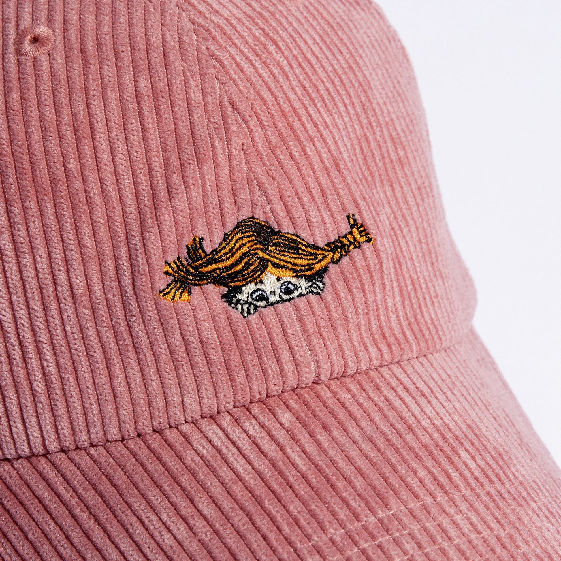soft pink corduroy dad cap from a low angle, resting on a cozy textured surface