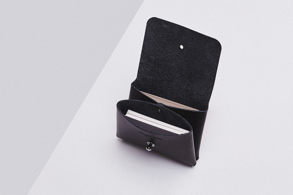 playful shot of a minimalist leather pouchie wallet with its colorful strap on a bright background