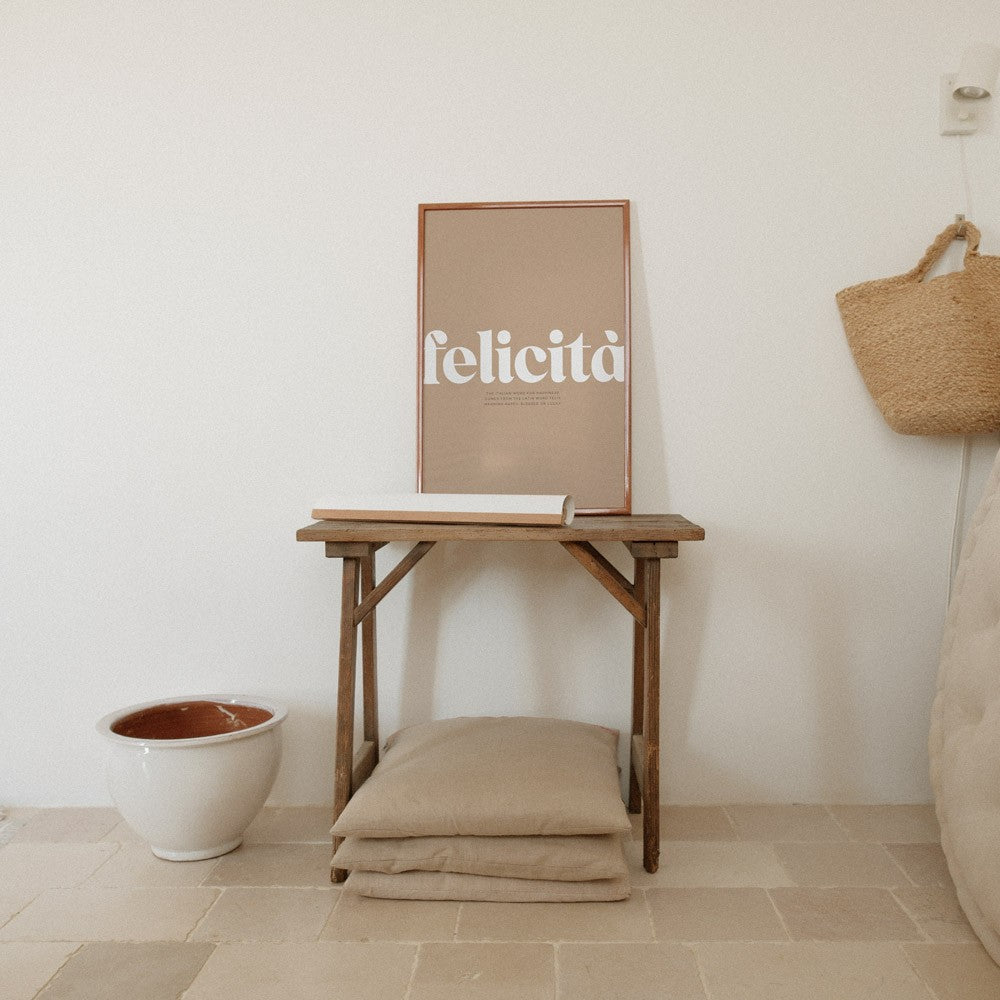 playful italian typography poster felicita on a bright studio wall with warm morning light