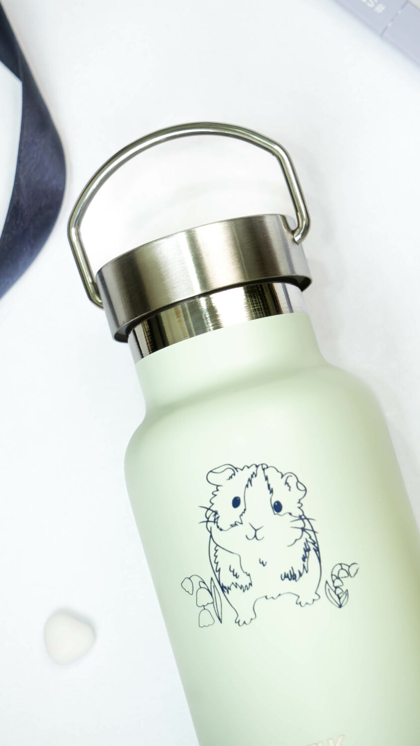 a soft green guinea pig thermos held in hand, showcasing its comforting and leakproof design